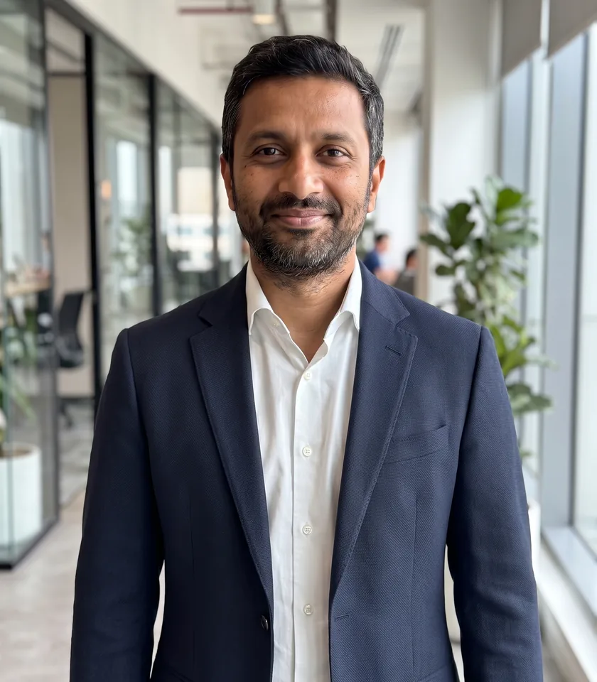 Before and after: the same man's grey T-shirt becomes a navy blazer over a white shirt, while his face and the office behind him stay the same